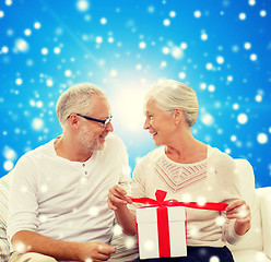 Image showing happy senior couple with gift box at home