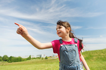 Image showing happy little girl pointing finger on summer field