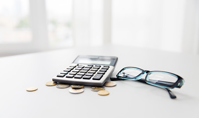 Image showing calculator, eyeglasses and coins on office table