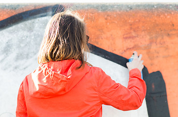 Image showing woman drawing graffiti with spray paint from back