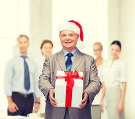 Image showing smiling man in suit and santa helper hat with gift