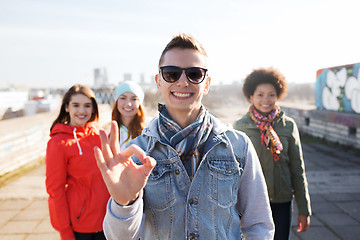 Image showing happy teenage friends showing ok sign on street