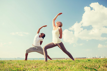 Image showing smiling couple making yoga exercises outdoors