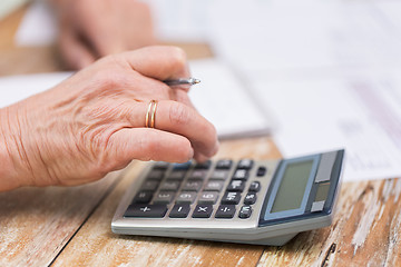 Image showing close up of senior woman counting with calculator