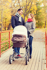 Image showing smiling couple with baby pram in autumn park