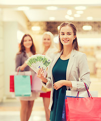 Image showing young women with shopping bags and money in mall