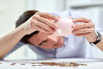 Image showing businessman with piggy bank and coins at office