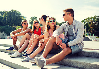 Image showing group of smiling friends sitting on city street