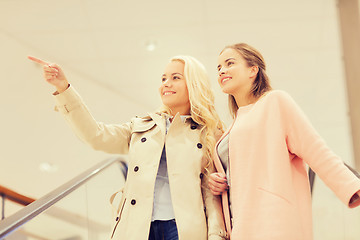 Image showing young women pointing finger on escalator in mall