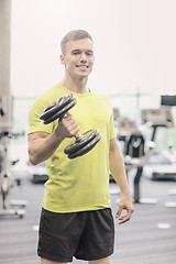 Image showing smiling man with dumbbell in gym