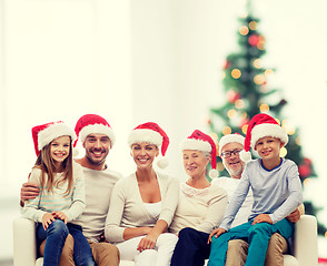 Image showing happy family in santa helper hats sitting on couch