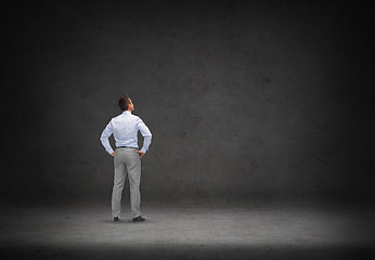 Image showing businessman looking at concrete wall background