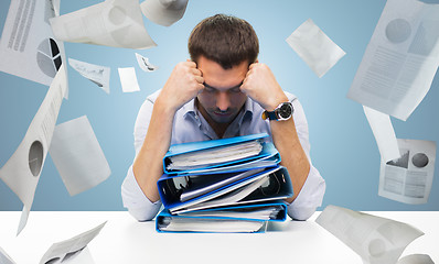 Image showing sad businessman with stack of folders at office