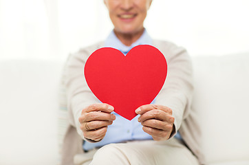 Image showing close up of senior woman with red heart at home