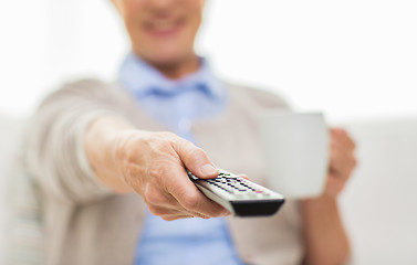 Image showing senior woman watching tv and drinking tea at home