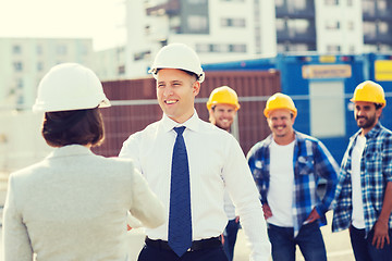 Image showing group of smiling builders in hardhats outdoors