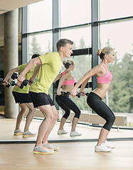 Image showing smiling man and woman with dumbbells in gym