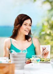 Image showing girl eating in cafe on the beach