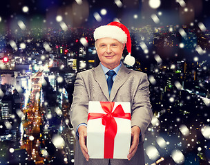 Image showing smiling man in suit and santa helper hat with gift