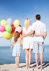 Image showing happy family at the seaside with bunch of balloons