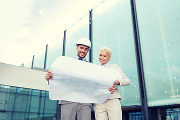 Image showing smiling businessmen with blueprint and helmets