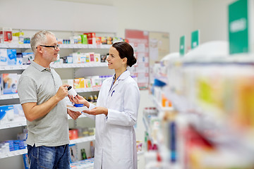 Image showing pharmacist and senior man buying drug at pharmacy