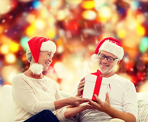 Image showing happy senior couple in santa hats with gift box