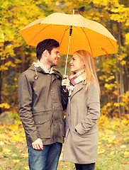 Image showing smiling couple with umbrella in autumn park