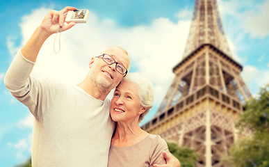 Image showing senior couple with camera over eiffel tower