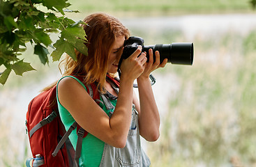 Image showing young woman with backpack and camera outdoors