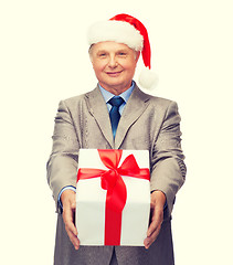 Image showing smiling man in suit and santa helper hat with gift