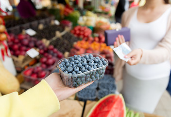 Image showing pregnant woman with money buying berries at market