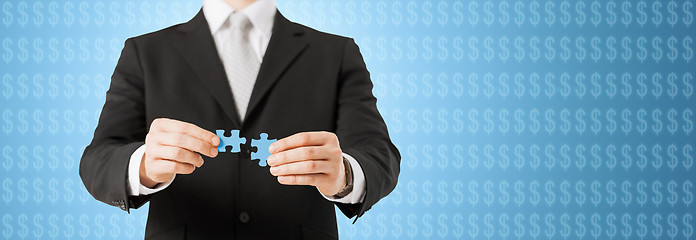 Image showing man matching puzzle pieces over blue background