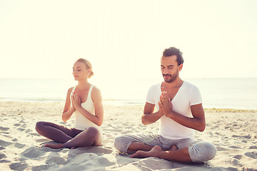 Image showing smiling couple making yoga exercises outdoors