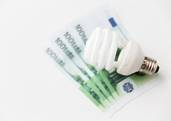 Image showing close up of euro money and lightbulb on table