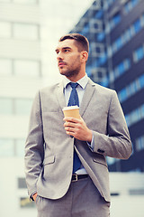 Image showing young serious businessman with paper cup outdoors