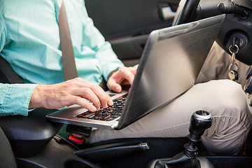 Image showing close up of young man with laptop driving car