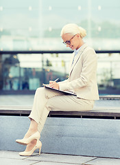 Image showing young smiling businesswoman with notepad outdoors