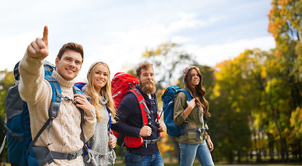 Image showing smiling friends with backpacks hiking over nature