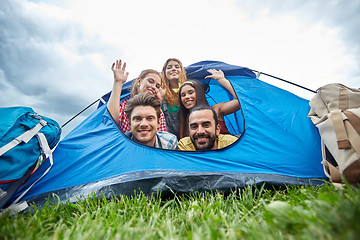 Image showing happy friends with backpacks in tent at camping