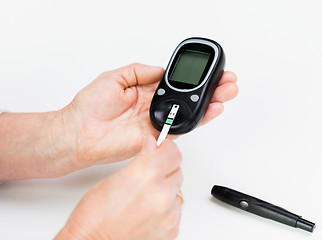 Image showing senior woman with glucometer checking blood sugar