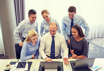 Image showing smiling business people with laptop in office