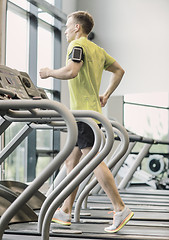 Image showing man with smartphone exercising on treadmill in gym