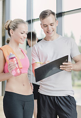 Image showing smiling young woman with personal trainer in gym