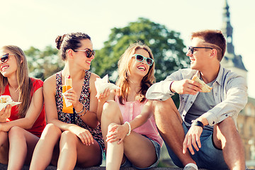 Image showing group of smiling friends sitting on city square