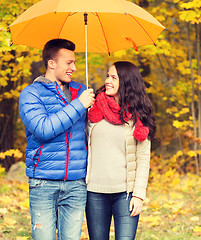 Image showing smiling couple with umbrella in autumn park