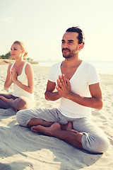 Image showing smiling couple making yoga exercises outdoors