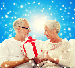 Image showing happy senior couple with gift box at home