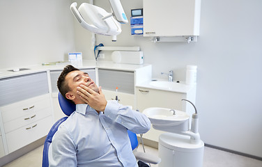 Image showing man having toothache and sitting on dental chair