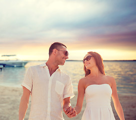 Image showing smiling couple in sunglasses walking on beach